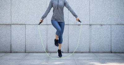 Woman jumping rope for her sprint interval training in front of a grey wall