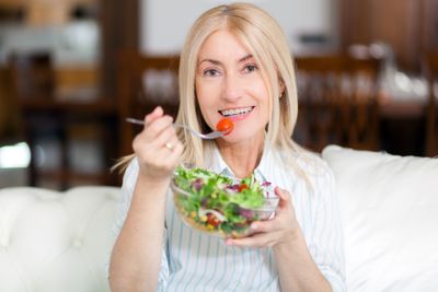 Blonde woman eating a salad and smiling