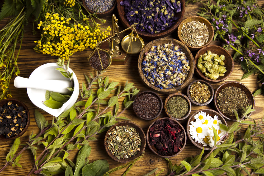An assortment of herbs and spices in bowls on a wooden table