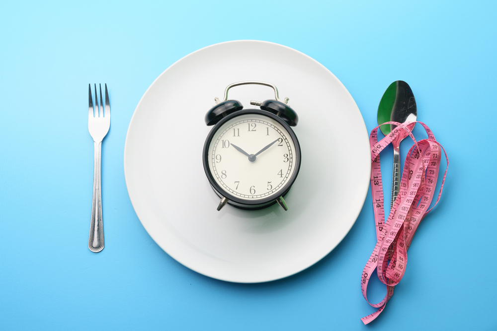 A spoon and fork next to a plate with a clock on a table