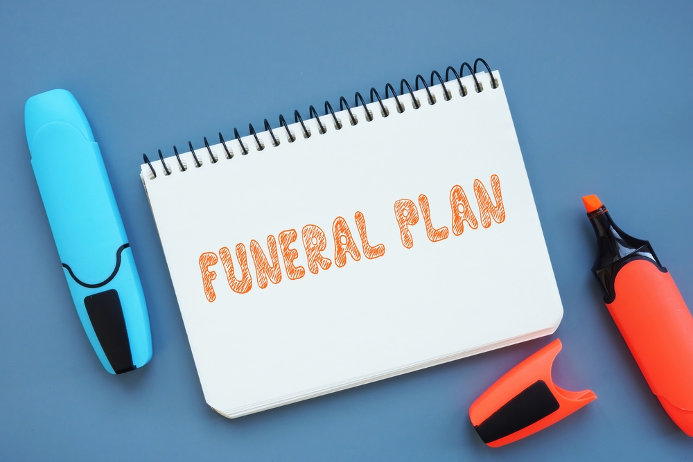 Paper notebook with orange and blue highlighter and text that reads "funeral plan"