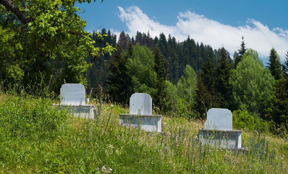 Three graves on a grassy green hillside