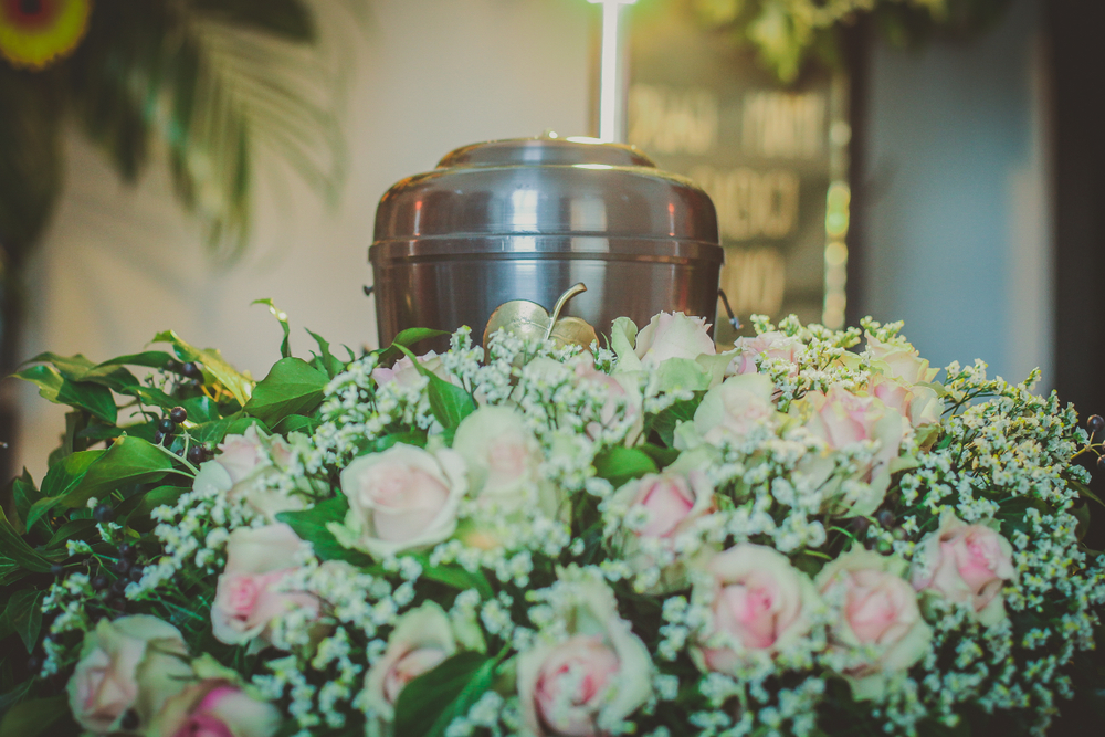 Metallic silver urn surrounded by pink roses