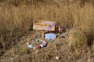 Grassy field with colored burial stones and painted sign that reads "our beautiful now flys with the butterflies"