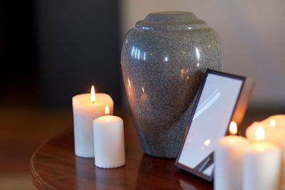 A cremation urn set on a side table, along with a few candles and a photo frame.