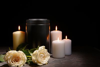 A black urn with candles  and 2 roses around it