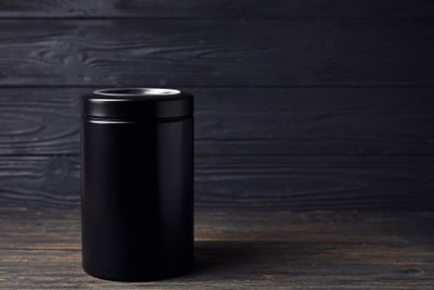 A black urn on a dark wooden table