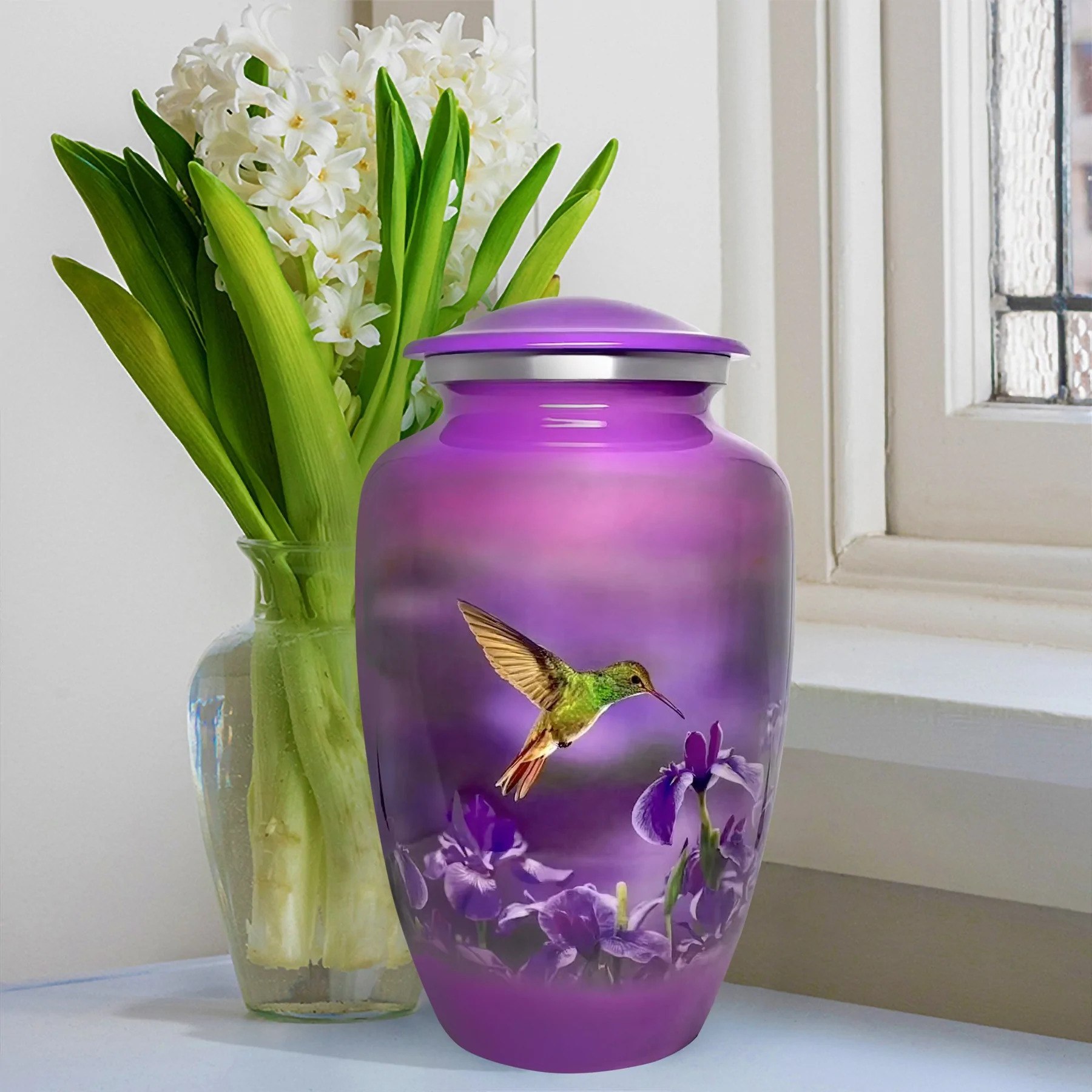 A purple urn depicting a hummingbird on a window sill in front of a vase with flowers