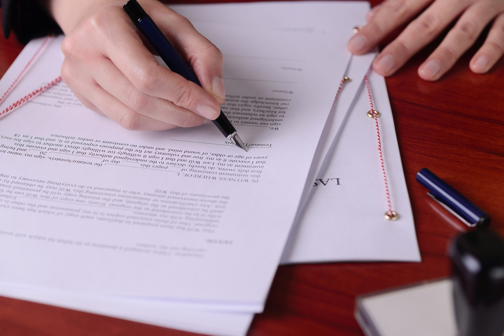 A person signing a testamentary letter with a pen