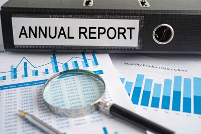 File that reads "Annual report" on top of other documents and a magnifying glass on a desk