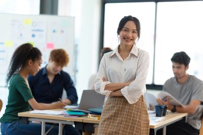 Smiling young businesswomen standing in front of her team while they work