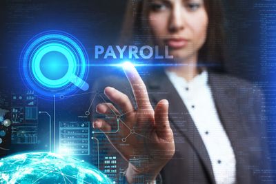 Woman in business attire holding holding her finger to a hovering graphic that reads "payroll"