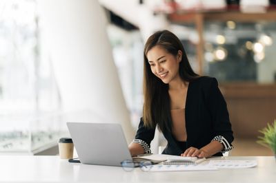 Woman in an office looking at her laptop and smiling