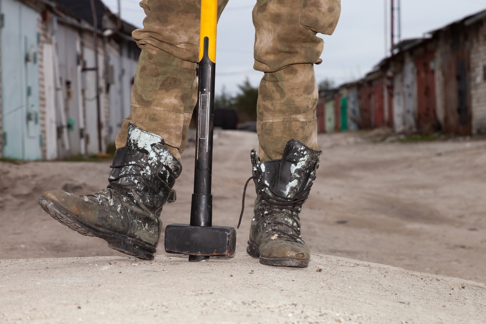 Person wearing work boots holding a sledgehammer