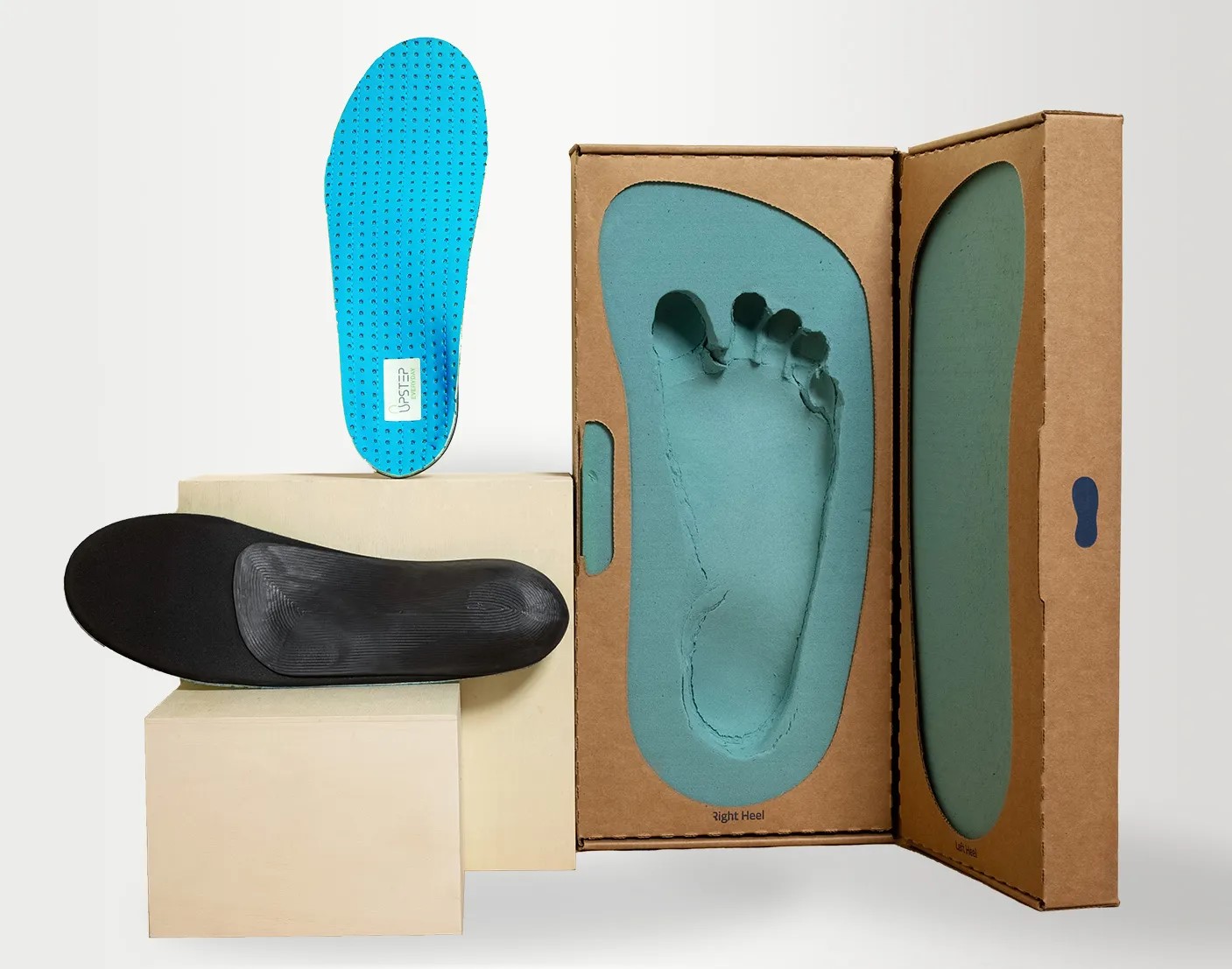 Upstep custom orthotics for heel pain displayed on pedestals with a foot cast on the right