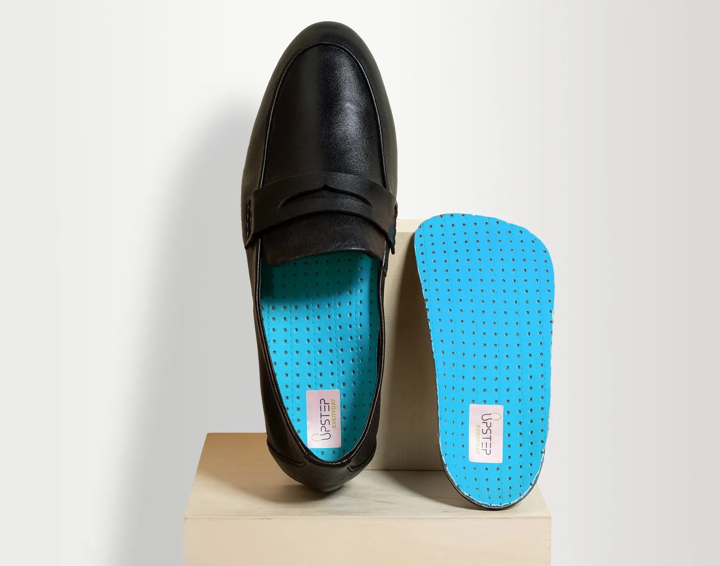 Upstep custom orthotics displayed vertically , one insole inside a formal shoe and the other outside