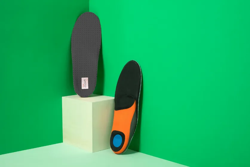A pair of Upstep running orthotics displayed vertically, one on a pedestal 