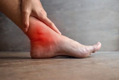 Man holding his ankle. Red spot on ankle area