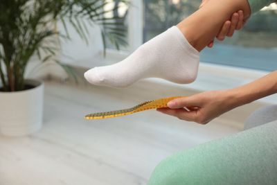 A person fitting an insole to the bottom of their foot.