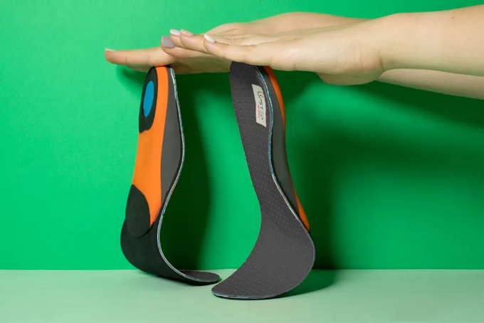 Hands displaying Upstep custom  fitness walking and hiking custom orthotics vertically