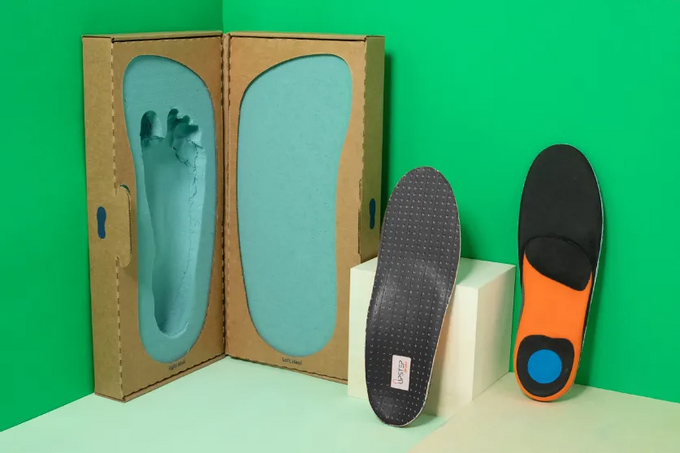 Vertically displayed Upstep running orthotics in grey and orange next to a foot cast