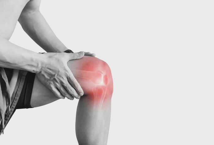Man holding knee with red-highlighted spot to indicate pain