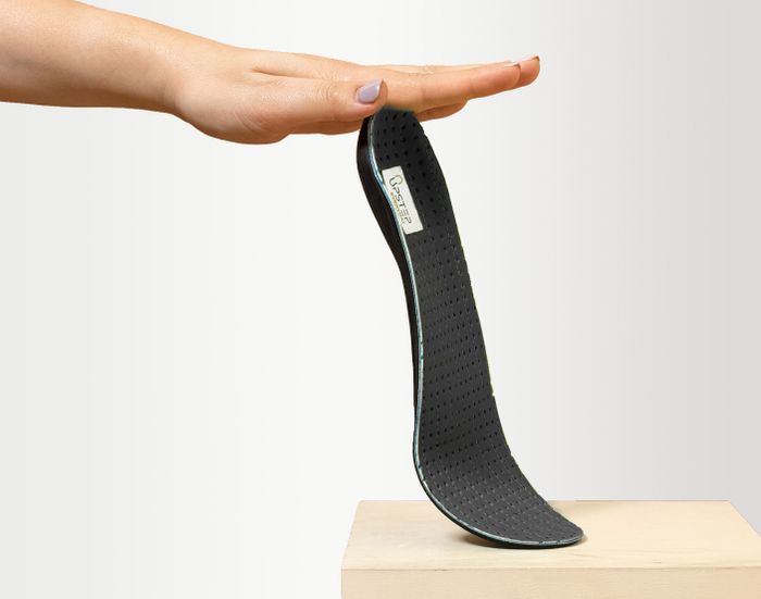 A hand holding up a custom insole for flat feet