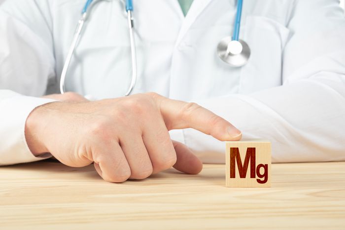 A doctor putting his finger on a wooden block with the letters mg for Magnesium