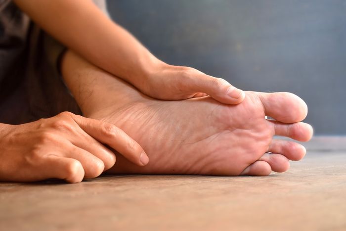 A person inspecting the sole of their foot with both hands  preview image