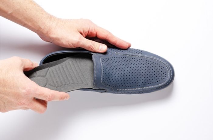 A person putting a heel spur insert into their shoe 