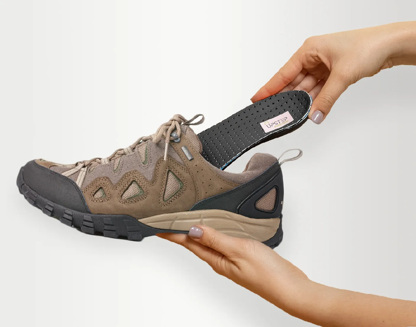 Placing Upstep's On My Feet All Day shoe orthotics into a brown hiking shoe.