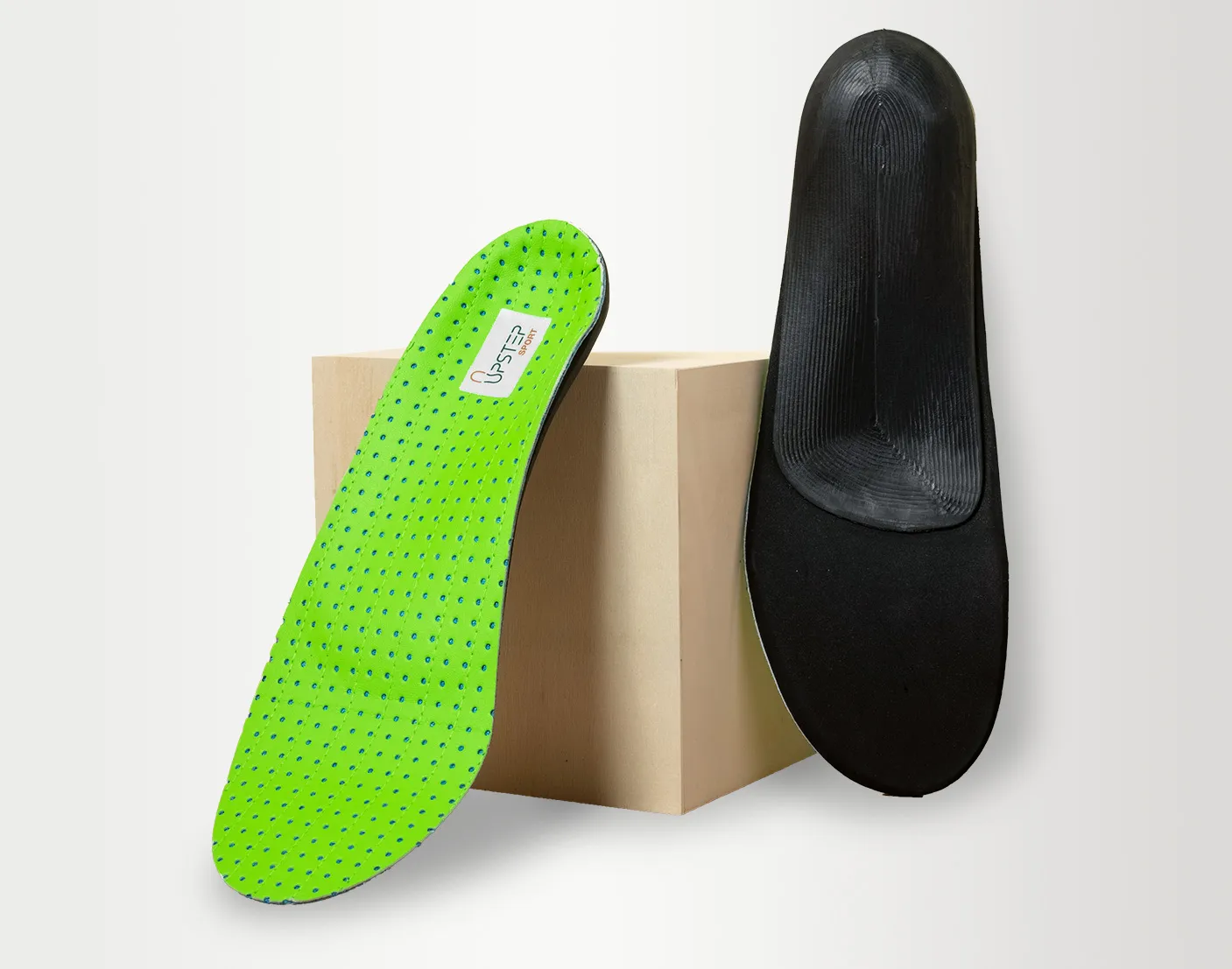 Upstep's custom supination shoe insole leaning on a box, next to a formal shoe.